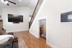 Living area featuring lofted ceiling, stairway, ceiling fan, and wood finished floors