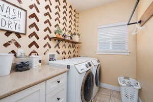 Laundry room with independent washer and dryer and light tile patterned floors