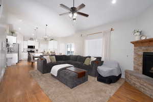 Living area with wood finished floors, recessed lighting, a ceiling fan, a stone fireplace, and high vaulted ceiling