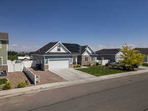Craftsman inspired home with a gate, roof mounted solar panels, driveway, a garage, and stone siding