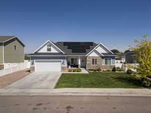 Craftsman-style home with stone siding, concrete driveway, solar panels, and a shingled roof