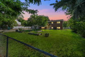 Yard at dusk featuring a garden and a fenced backyard