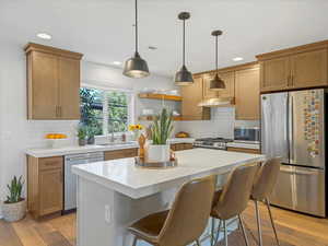 Kitchen featuring stainless steel appliances, light wood-style floors, backsplash, recessed lighting, and light countertops