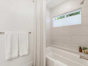 Full bath featuring shower / bathtub combination with curtain and baseboards