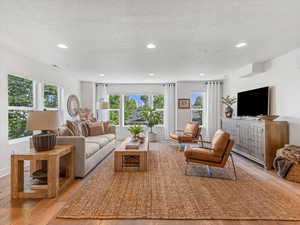Living room featuring light wood-style floors, a textured ceiling, and recessed lighting