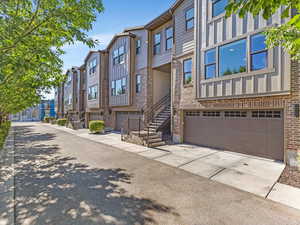 View of building exterior with a residential view, a garage, driveway, and stairs