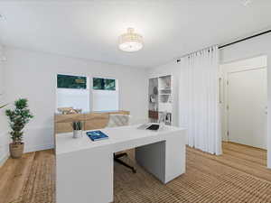 Home office featuring light wood-style floors and a textured ceiling