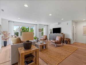 Living area with light wood-type flooring, a textured ceiling, and recessed lighting