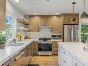 Kitchen featuring appliances with stainless steel finishes, open shelves, recessed lighting, light countertops, and decorative light fixtures