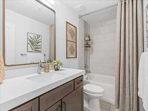 Full bathroom featuring vanity, shower / bath combo with shower curtain, a textured ceiling, and tile patterned floors