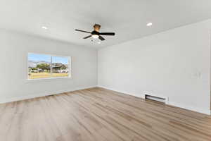 Spare room featuring light wood-style floors, recessed lighting, ceiling fan, and a baseboard radiator