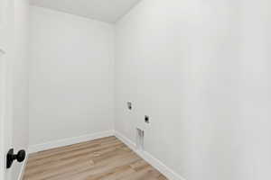 Laundry room with electric dryer hookup, light wood finished floors, and hookup for a washing machine