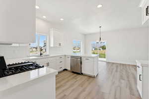 Kitchen featuring healthy amount of natural light, a peninsula, a chandelier, backsplash, and recessed lighting