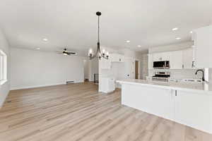 Kitchen featuring a ceiling fan, a peninsula, decorative backsplash, appliances with stainless steel finishes, and light countertops
