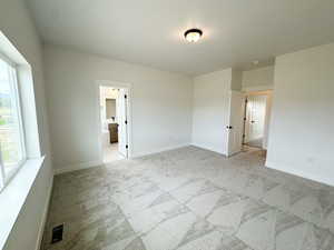 Unfurnished bedroom featuring light carpet and ensuite bath