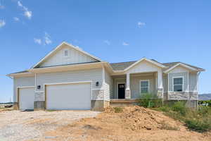 Craftsman-style home with stone siding, board and batten siding, a garage, a porch, and driveway