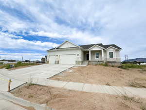 Ranch-style house featuring board and batten siding, a shingled roof, concrete driveway, and stone siding