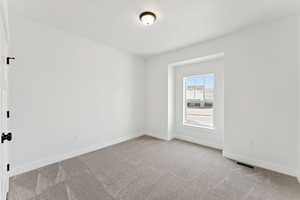 Carpeted spare room featuring baseboards