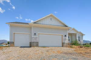 View of front of house with stone siding, driveway, board and batten siding, and an attached garage