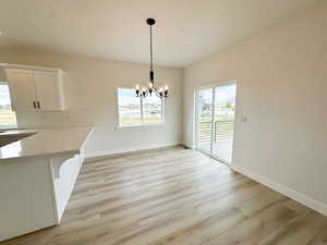 Unfurnished dining area featuring a chandelier and light wood-style flooring