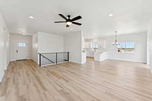 Unfurnished living room with healthy amount of natural light, a chandelier, light wood-type flooring, and recessed lighting