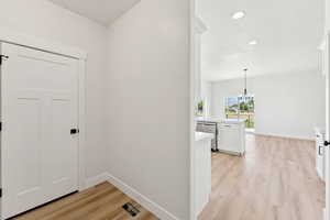 Corridor featuring light wood-type flooring, a chandelier, and recessed lighting