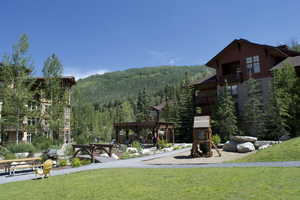 View of jungle gym featuring a forest view, a lawn, and a mountain view