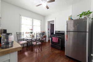 Kitchen with freestanding refrigerator, gas stove, ceiling fan, dark wood finished floors, and a textured ceiling