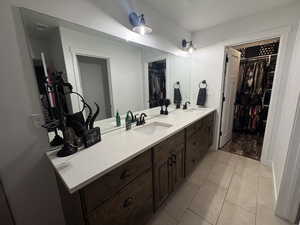 Bathroom featuring double vanity, a walk in closet, and tile patterned floors