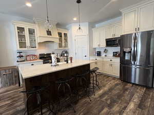 Kitchen with stainless steel appliances, light countertops, a breakfast bar area, dark wood-type flooring, and pendant lighting