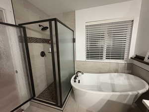 Full bathroom with a freestanding bath, a shower stall, and tile patterned floors