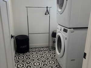 Washroom with stacked washer and clothes dryer and tile patterned flooring