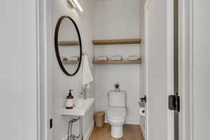 Half bathroom with toilet and wood finished floors