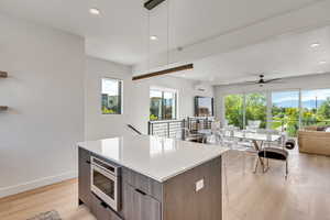 Kitchen with modern cabinets, open floor plan, a kitchen island, light wood-style floors, and ceiling fan