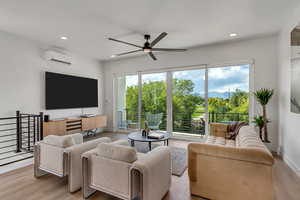 Living area with a ceiling fan, recessed lighting, wood finished floors, and a wall mounted air conditioner