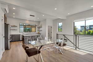 Dining space with light wood finished floors, recessed lighting, a wall mounted AC, and beam ceiling