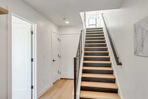 Staircase with wood finished floors and baseboards
