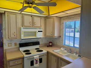 Kitchen featuring white appliances, light countertops, and ceiling fan