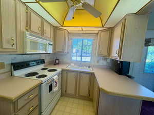 Kitchen featuring white appliances, light flooring, a ceiling fan, light countertops, and wallpapered walls