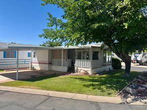 View of front of home featuring a porch, a front yard, a carport, and driveway
