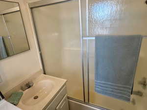 Bathroom featuring vanity and combined bath / shower with glass door