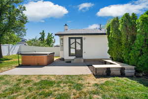 Back of property with a hot tub, a fenced backyard, a patio area, and a chimney