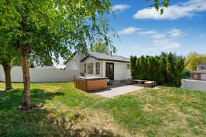 Back of property featuring a hot tub, a patio area, and a fenced backyard