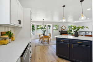 Kitchen featuring white cabinets, light countertops, light wood-style flooring, hanging light fixtures, and recessed lighting
