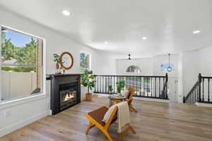 Living area with a textured ceiling, recessed lighting, wood finished floors, ceiling fan, and an upstairs landing