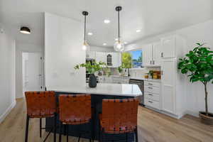 Kitchen with a kitchen breakfast bar, white cabinetry, light countertops, stainless steel appliances, and recessed lighting