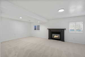Unfurnished living room with carpet floors, recessed lighting, and a glass covered fireplace