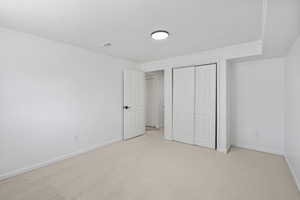 Unfurnished bedroom featuring light colored carpet, crown molding, and a closet