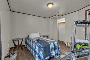 Bedroom with wood tiled floors and crown molding