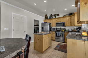 Kitchen with washer and clothes dryer, appliances with stainless steel finishes, dark countertops, a kitchen island, and recessed lighting
